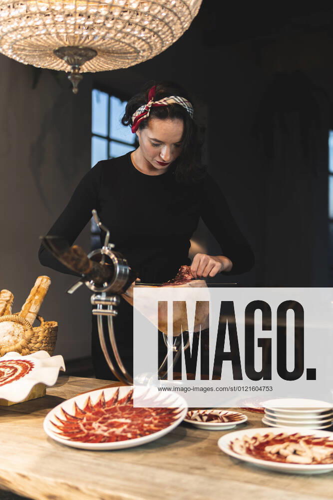 Female owner cutting meat on ham holder at restaurant model released Symbolfoto property released JAQF00556