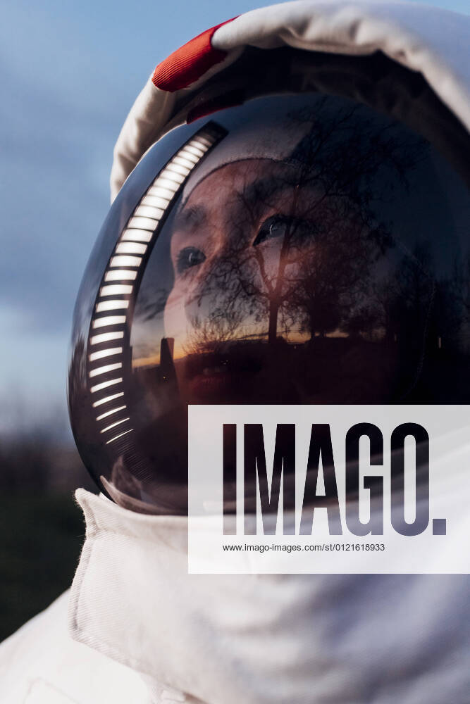IMAGO Creative: 2022 Aussichten Female astronaut looking away with reflection of illuminated light on helmet during sunset model released Symbolfoto property released MEUF02500