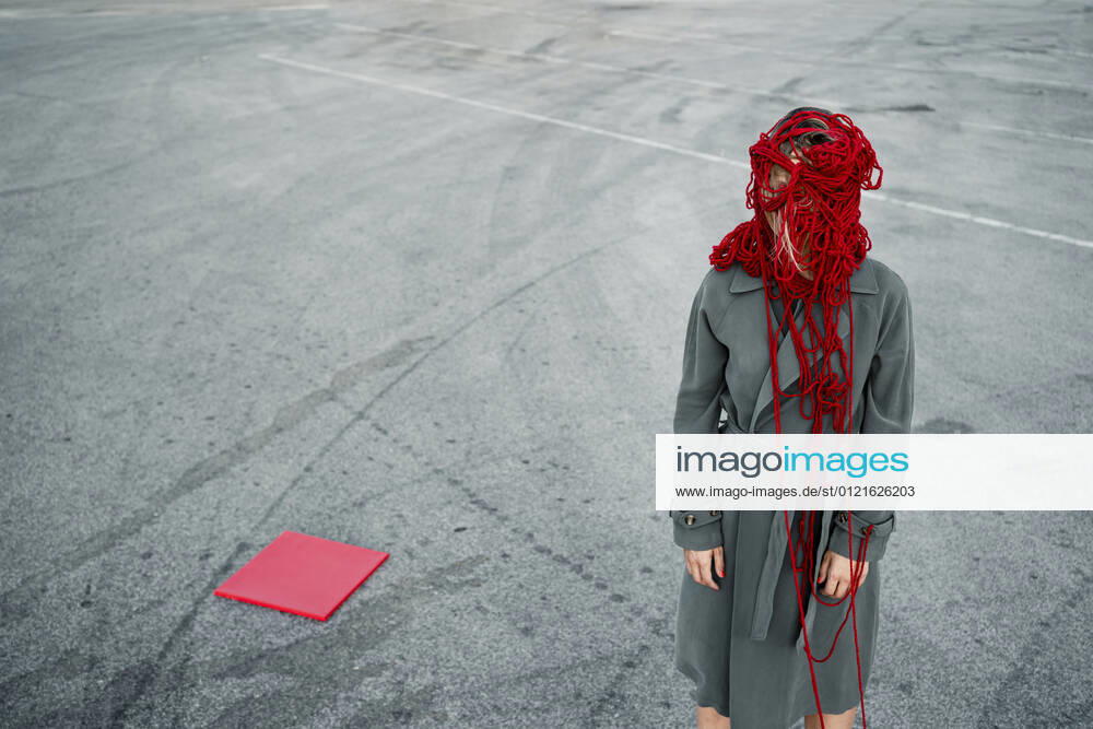 Woman covering face with thread while standing by red placard on road model released Symbolfoto RCPF00996
