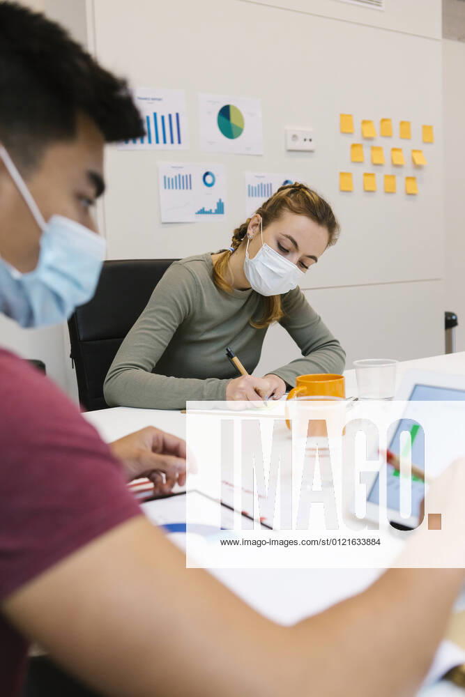 IMAGO Creative: 2022 Aussichten Businessman and female coworker working at desk in coworking office during COVID-19 model released Symbolfoto property released XLGF01549