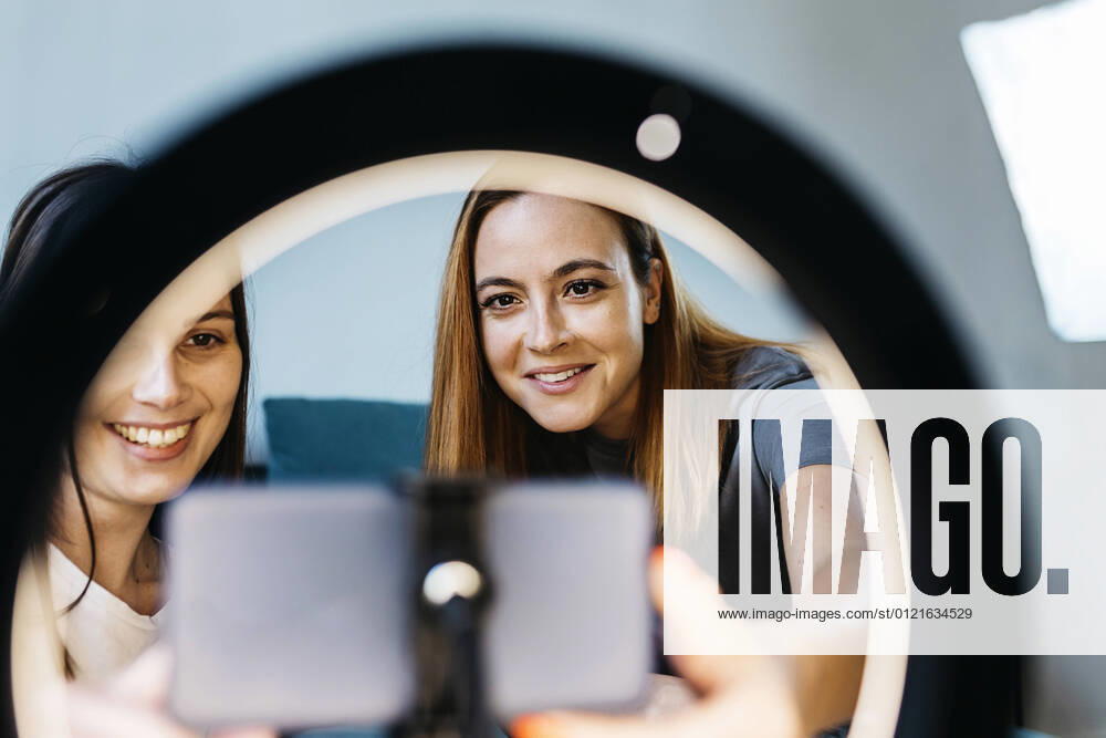 IMAGO Creative: Digitale Welt, Social Commerce Smiling female influencers vlogging using mobile phone at home model released Symbolfoto property released XLGF01733