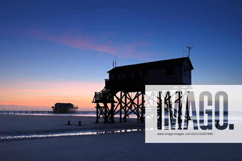 Pile houses at low tide on the beach at sunset, St Peter Ording, Schleswig Holstein Wadden Sea National Park, Schleswig Holstein, Germany, Europe
