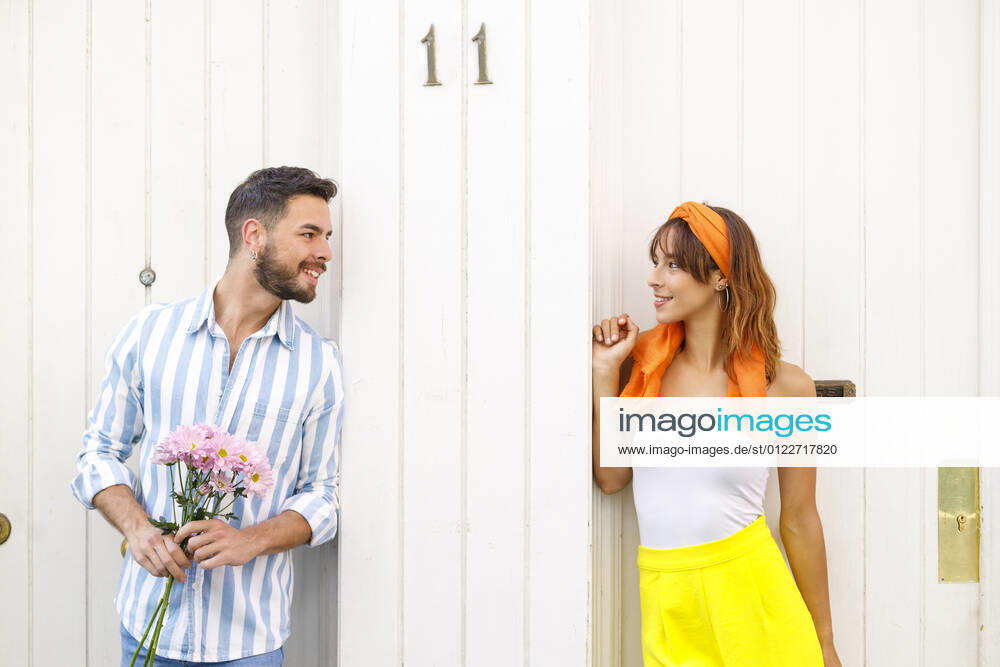 Young man with bunch of flowers looking at woman standing in front of door model released Symbolfoto IFRF00797