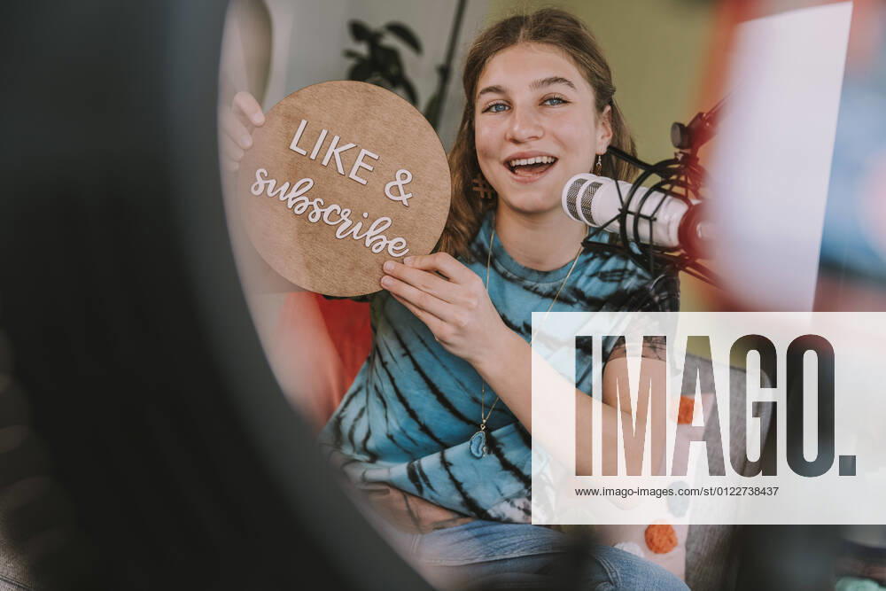 Girl showing like and subscribe sign while vlogging at home model released Symbolfoto property released MFF08035