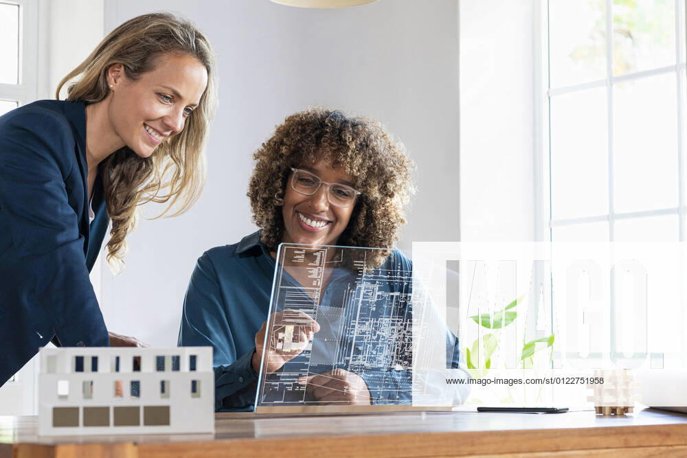 Mid adult businesswomen planning strategy on futuristic digital tablet at office model released Symbolfoto property released SBOF03979