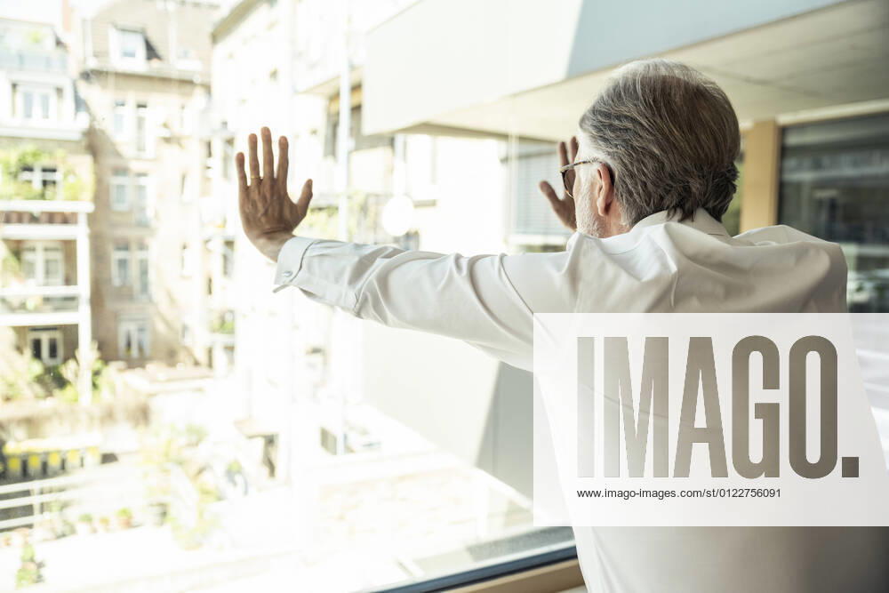 Male professional touching glass window while leaning at office model released Symbolfoto property released UUF23486