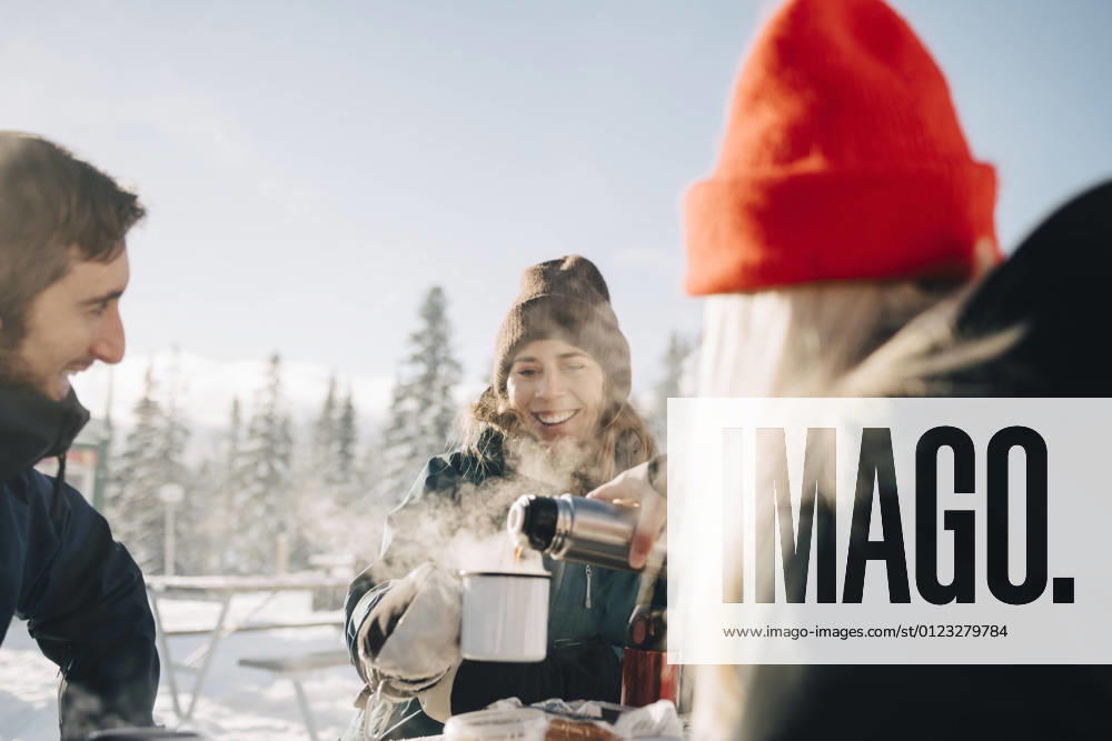 IMAGO Creative: Wintersport, Urlaub IMAGO Creative: Landleben - Essen IMAGO Creative: Landleben - Alfresco, Draußen Young woman pouring coffee for female friend during winter Sweden, ?re, model released