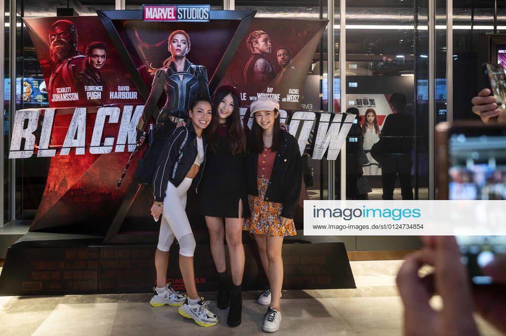 Spectators pose in front of Disney s and Marvel Studios movie banner for the screening of Black Widow film, played by Scarlett Johansson, at a movie theater in Hong Kong. Hong Kong China - ZUMAs197 20210707_zaa_s197_337