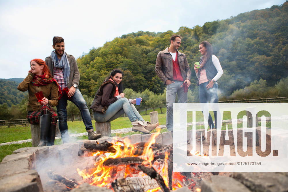 Group of people standing around campfire.