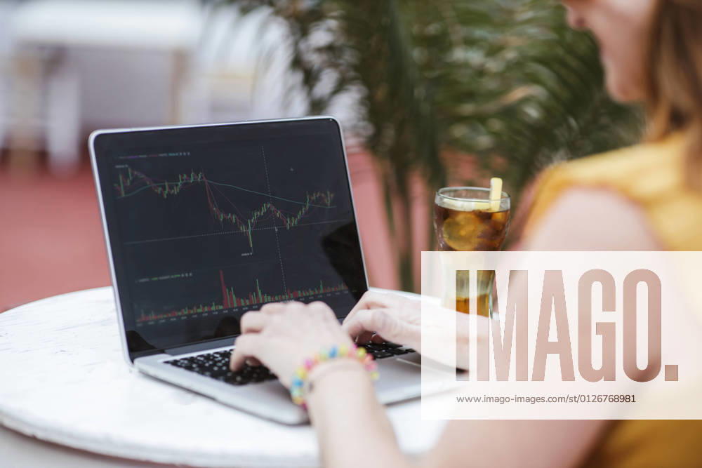 IMAGO Creative: 2022 Aussichten IMAGO Creative: 2021 Trends Woman trading on stock market through laptop at bar model released Symbolfoto property released LJF02198