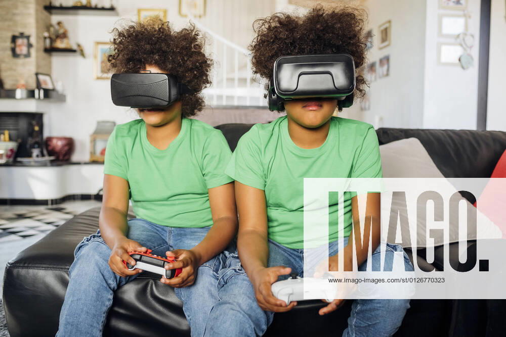 Twin brothers playing game wearing Virtual reality glasses at home model released Symbolfoto property released MEUF03416