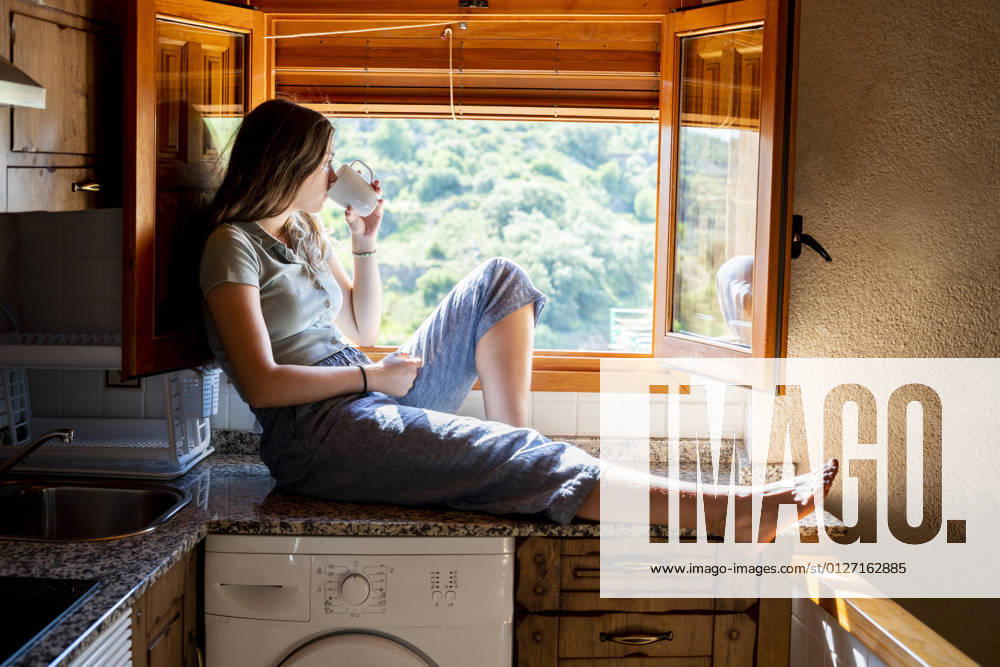 IMAGO Creative: Gesellschaft, Armut Teenage woman sitting looking out the window drinking coffee Valencia, Valencian Community, Spain CR_VFKDPR210721-801421-01 ,model released, Symbolfoto