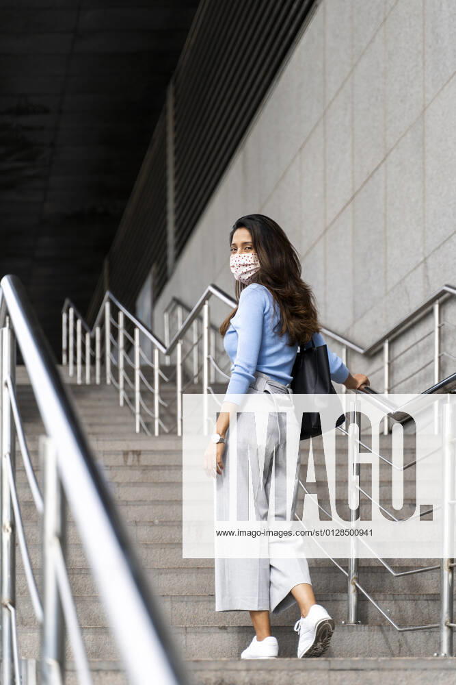 Contemplating woman with hand bag climbing staircase during COVID-19 model released Symbolfoto AFVF07549