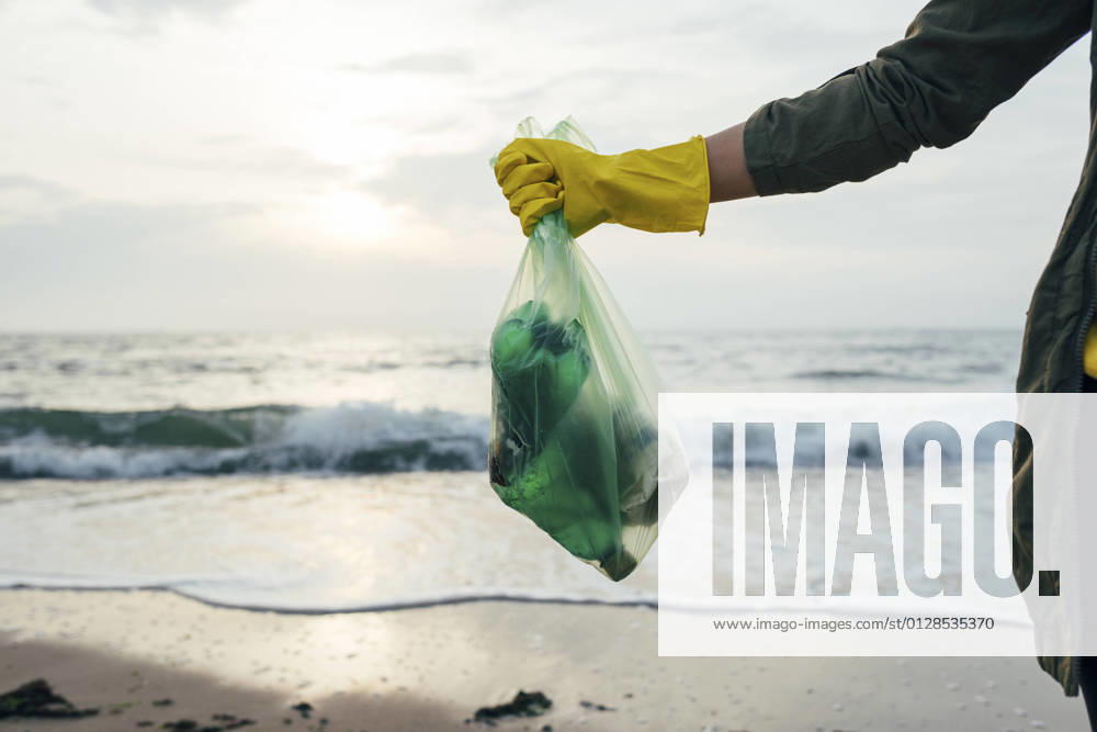 Mid adult woman holding garbage bag while standing at beach model released Symbolfoto OYF00248