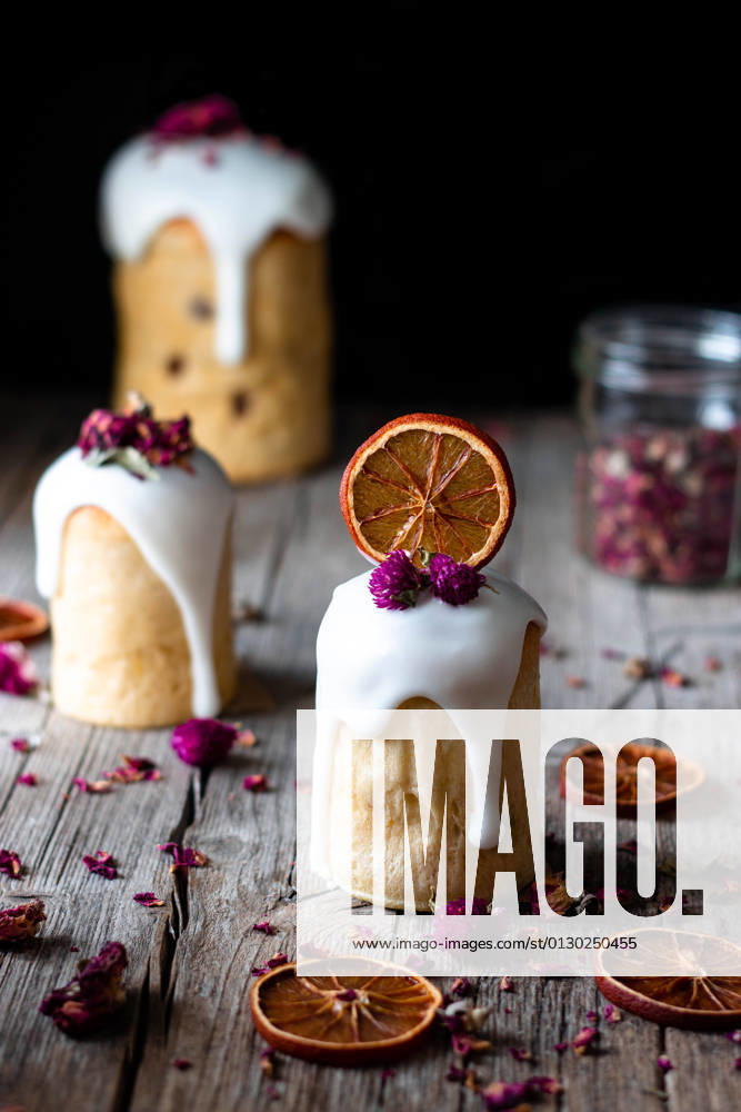 Several delicious homemade kulichs poured with sweet glaze and decorated with pieces of dry orange and flowers on wooden table PimientaDulce_VariousFood_80.jpg