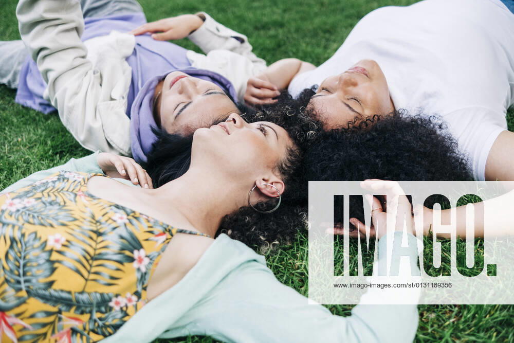 Young male and female friends lying on grass at park model released Symbolfoto ASGF00877