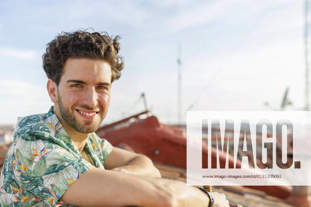 IMAGO Creative, Jahreszeit Sommer, Sommer in der Stadt Smiling young man on terrace during weekend model released Symbolfoto property released IFRF00991