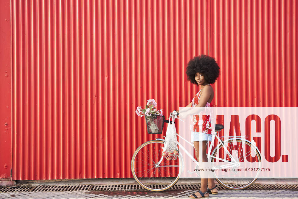 Afro woman with bicycle standing by red corrugated wall model released Symbolfoto VEGF04808