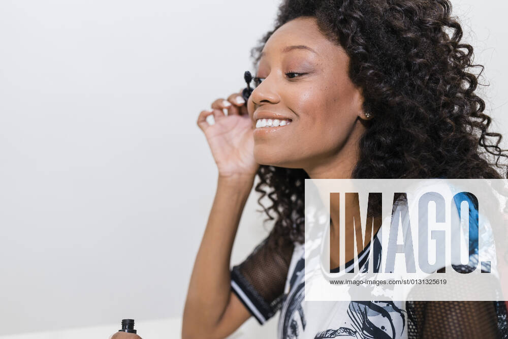 Smiling female make-up artist applying mascara in studio model released Symbolfoto JRVF01321