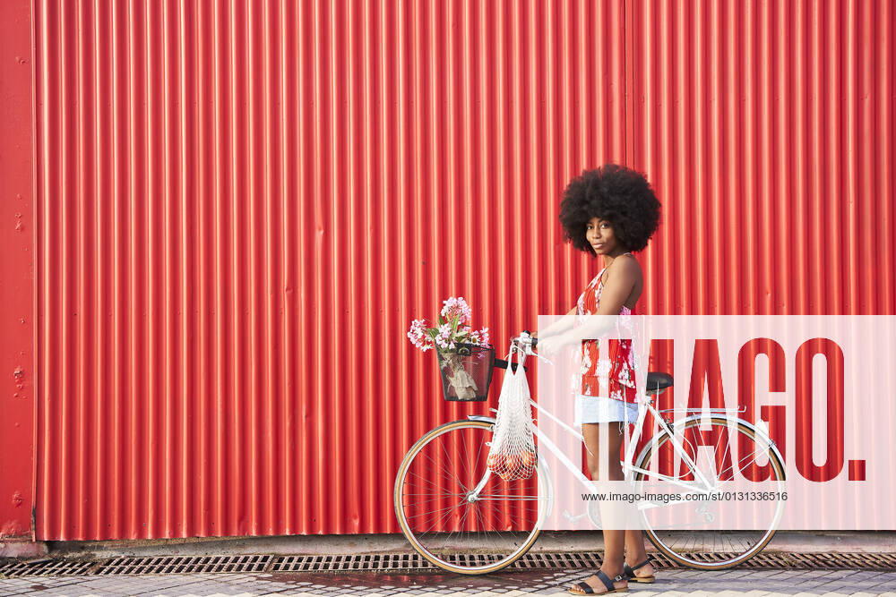 Afro woman with bicycle standing by red corrugated wall model released Symbolfoto VEGF04808