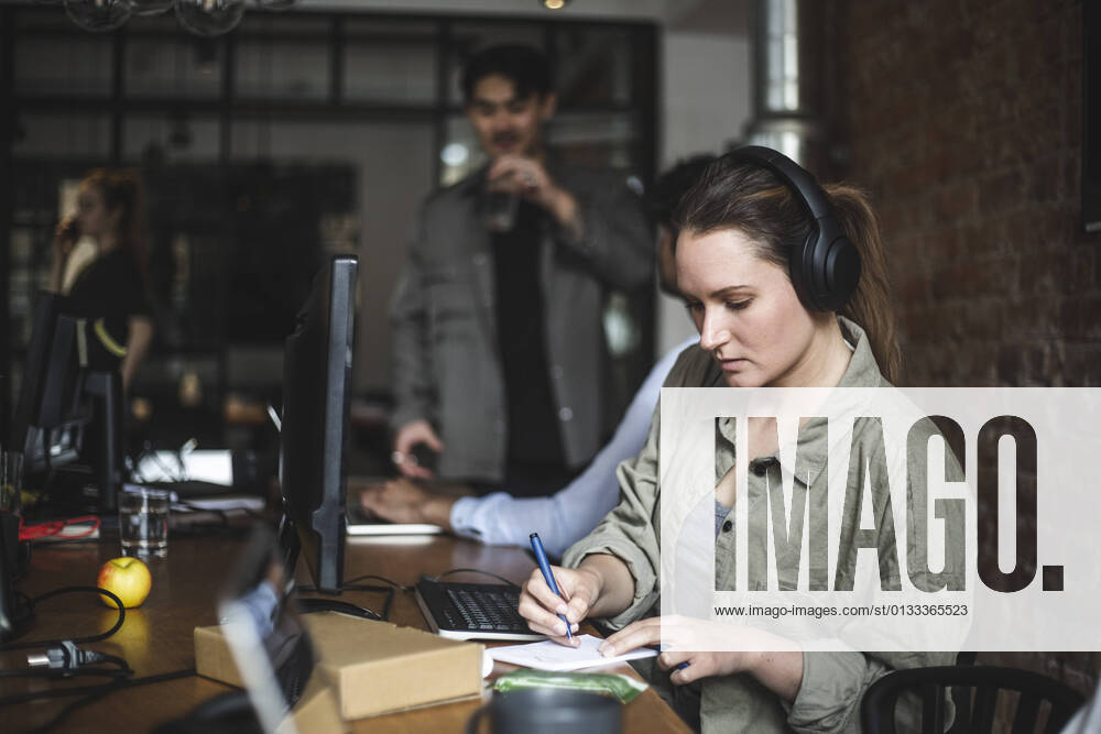 Businesswoman writing in note pad while working in office Sweden, Stockholm, model released, property released