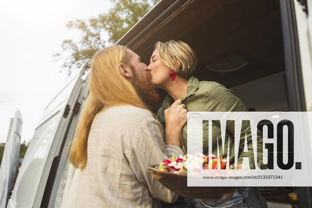 IMAGO Creative: Landleben - Essen IMAGO Creative: Landleben - Alfresco, Draußen Young couple kissing while standing in motor home during vacation Sweden, Gothenburg, model released, property released