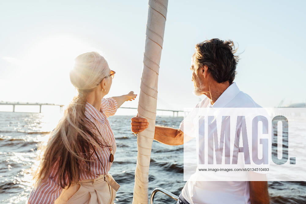 Rearview of two mature people sitting on a yacht bow. Loving senior couple enjoying a boat trip. Rearview of two mature people sitting on a yacht bow. Loving senior couple enjoying a boat trip.