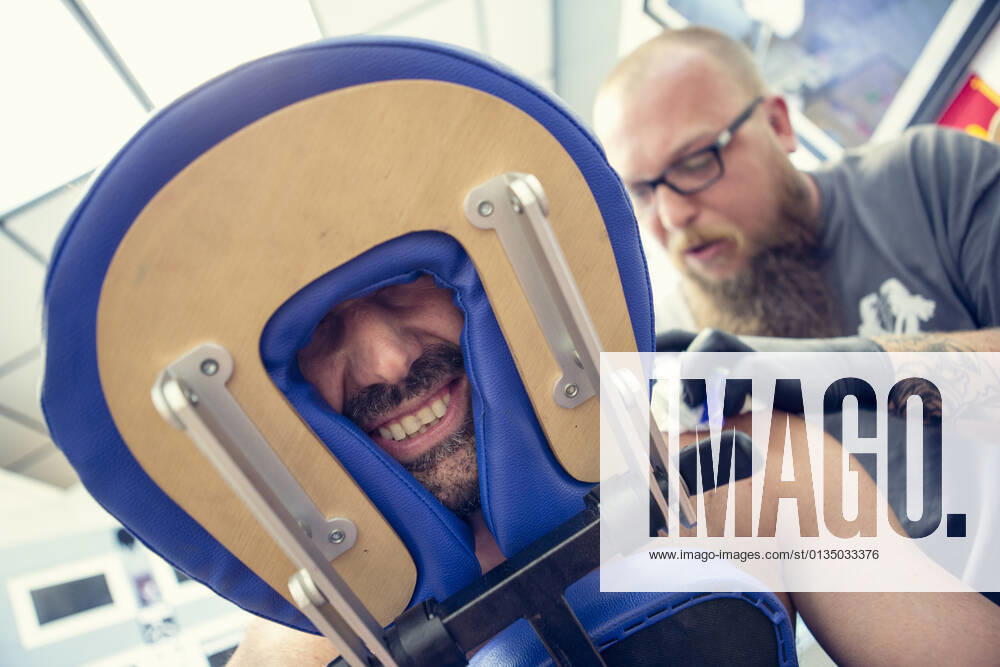Male customers face between headrest in tattoo parlor, 26.06.2014,