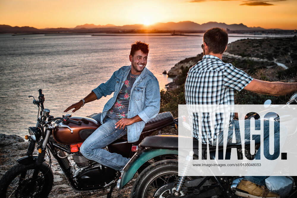 Portrait of two male motorcyclist friends on coast at sunset, Cagliari, Sardinia, Italy, 28.08.2014,