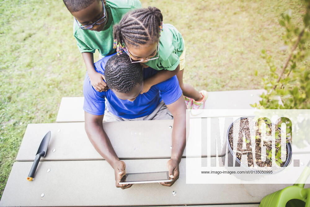 IMAGO Creative: Klimawandel - Umwelterziehung High angle view of father looking at digital tablet with daughter and son at eco camp, 01.09.2014,