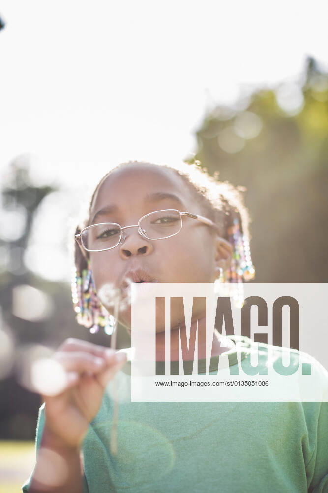 IMAGO Creative: Klimawandel - Umwelterziehung Portrait of girl blowing dandelion clock in parkland eco camp, 01.09.2014,