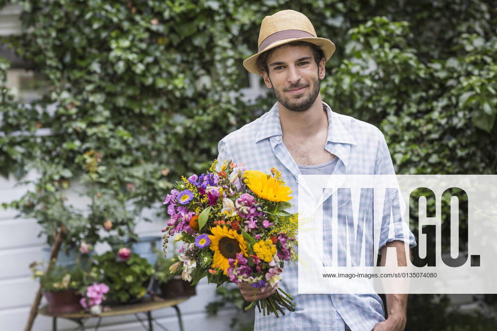 Portrait of young man with bunch of flowers in garden, 30.11.2014,