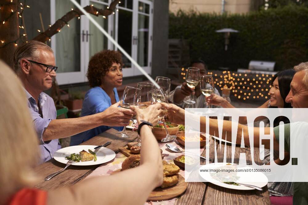 Group Of Mature Friends Enjoying Outdoor Meal In Backyard model released, Symbolfotoproperty released, , 11.10.2020,