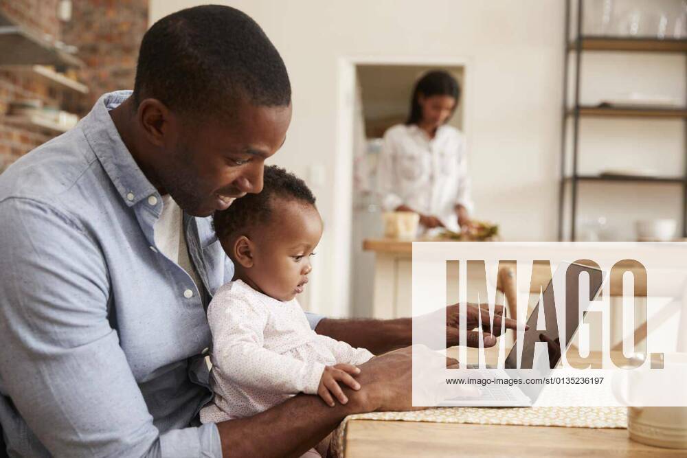 IMAGO Creative: 2022 Aussichten Father And Baby Daughter Use Laptop As Mother Prepares Meal model released, Symbolfotoproperty released, , 12.10.2020,