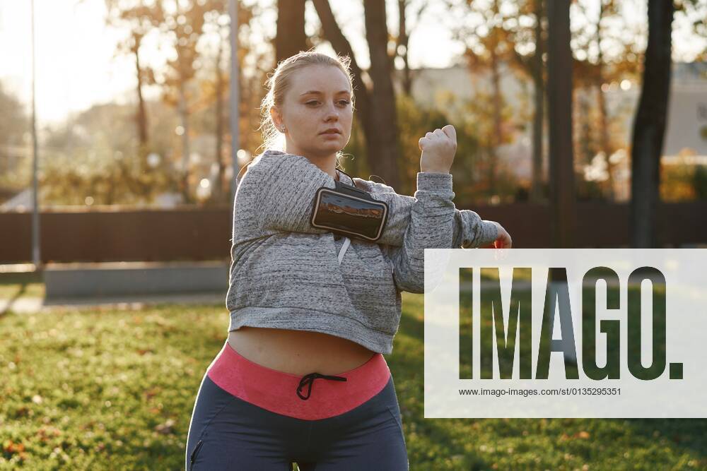 Curvaceous young woman training in park, stretching arms, 10.01.2018,