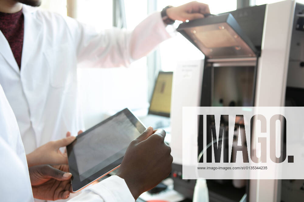 IMAGO Creative: Business, Innovative Technologie-Lösungen Young female and male scientists using digital tablet in laboratory, mid section, 21.05.2019,