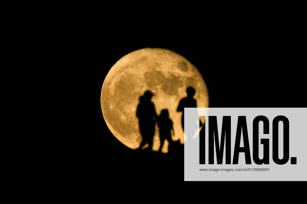 People are silhouetted against the backdrop of a full moon, also known as Harvest Moon , rises in Los Angeles, Tuesday, Sept. 21, 2021. Los Angeles USA - ZUMAc68_ 20210921_zaf_c68_012