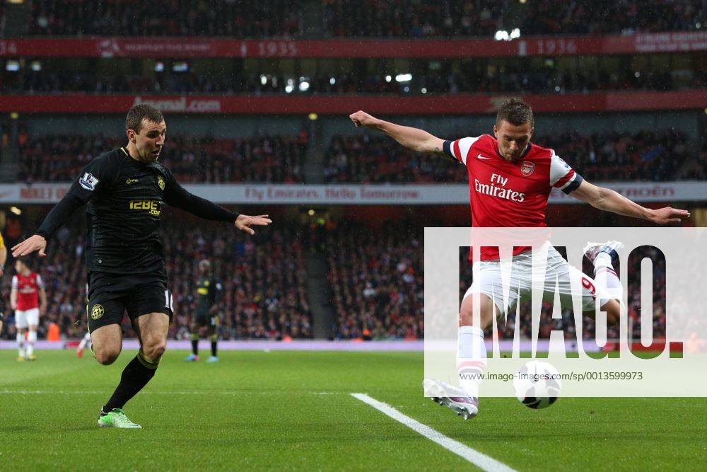 Football - 2012 2013 Premier League - Arsenal vs Wigan Lukas Podolski of Arsenal crosses while under pressure from Wigan s James McArthur at the Emirates Stadium, London