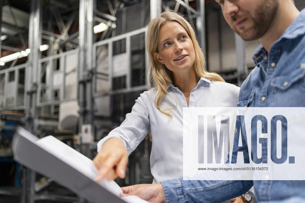 IMAGO Creative: Internationaler Frauenmonat, Geschlechterrollen aufbrechen IMAGO Creative: Corporate: Klimaschutz, Digitalisierung und Urbanisierung IMAGO Creative: Klimawandel - Zukunft und Innovation Businesswoman sharing expertise with colleague over plan at industry model released Symbolfoto property released DIGF16417