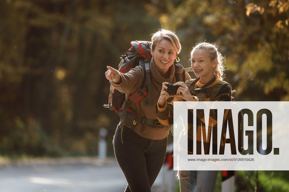 Fun In The Forest Shot of a teen girl and her mom using digital photo camera during walk together through the forest in autumn.
