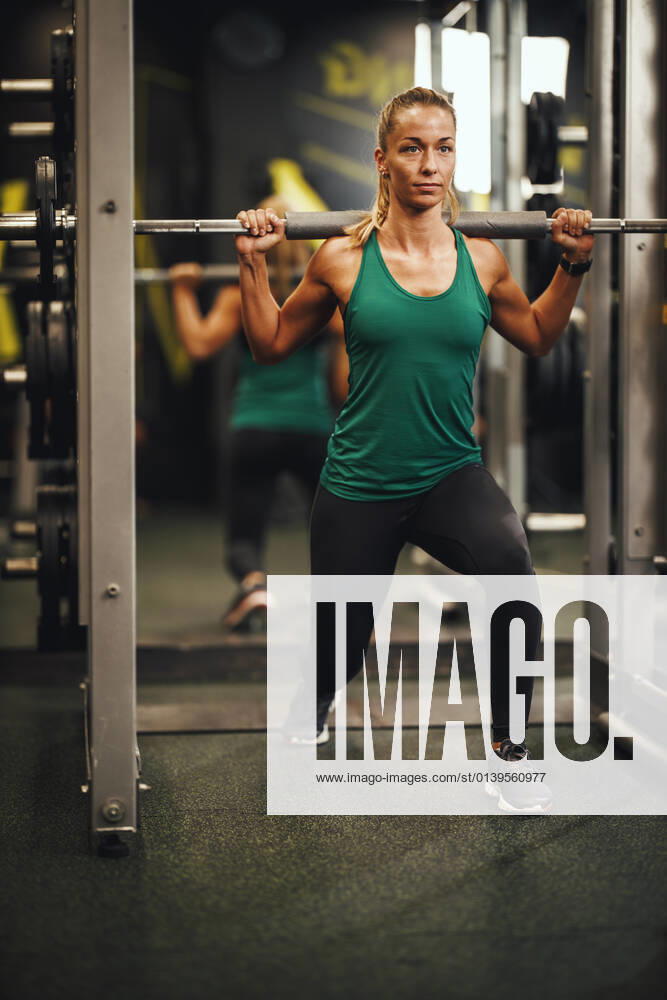 Stay Consistent, Stay Fit Shot of a muscular young woman in sportswear working out at the gym. She is doing lunge exercises with barbell.