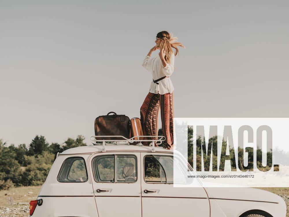 IMAGO Creative: Retro-Revival Full body side view of stylish female hippie in boho clothes standing on white old timer automobile with luggage during trip in nature, Model released HodeiUnzueta_HippiesOnTheRoad_9.jpg