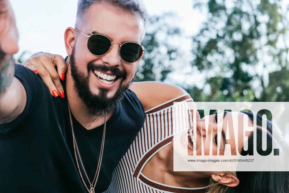 Happy female with black hair in casual clothes embracing cheerful boyfriend in sunglasses while laughing on street in daytime JoseDeJesusSaldana_Street_11.jpg
