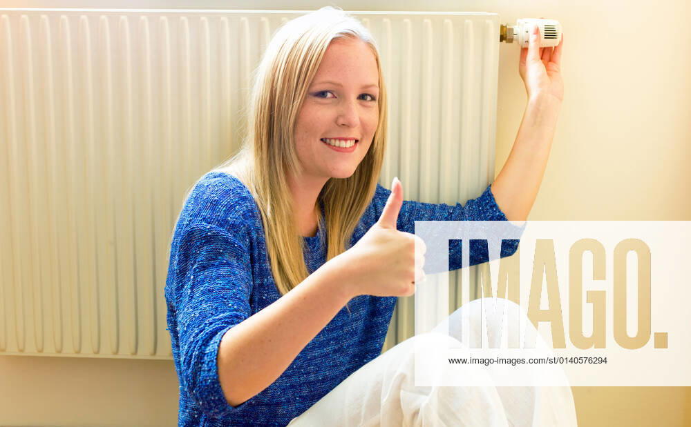 A young woman sits in winter in front of a heating cËÜrper McPBBO McPBBO