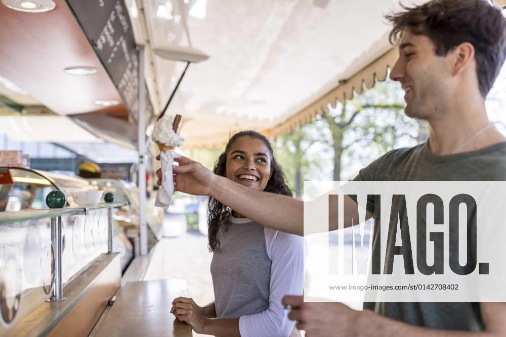 IMAGO Creative, Sommer, Schatten-Plätze bei Hitze Smiling woman looking at friend buying ice cream at park model released, WPEF05480