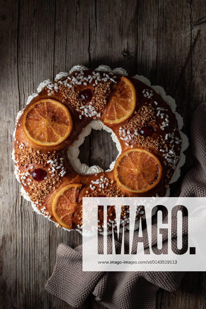 Overhead of king s cake with cream and sprinkles decorated with orange slices and cherries and placed on wooden surface near towel PimientaDulce_RosconOfKings_1.jpg