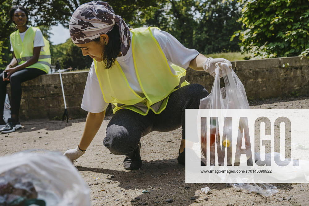 IMAGO Creative: Nächste Generation, Sozial- und klimabewusst Young female volunteer picking up plastic waste in park Germany, Berlin, model released