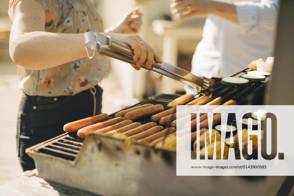 Midsection of woman preparing food on barbecue grill during garden party Sweden, Stockholm, model released, property released