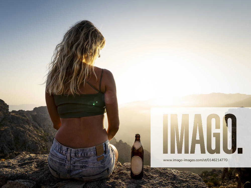 Woman with beer bottle enjoying sunset from mountain model released, MALF00372