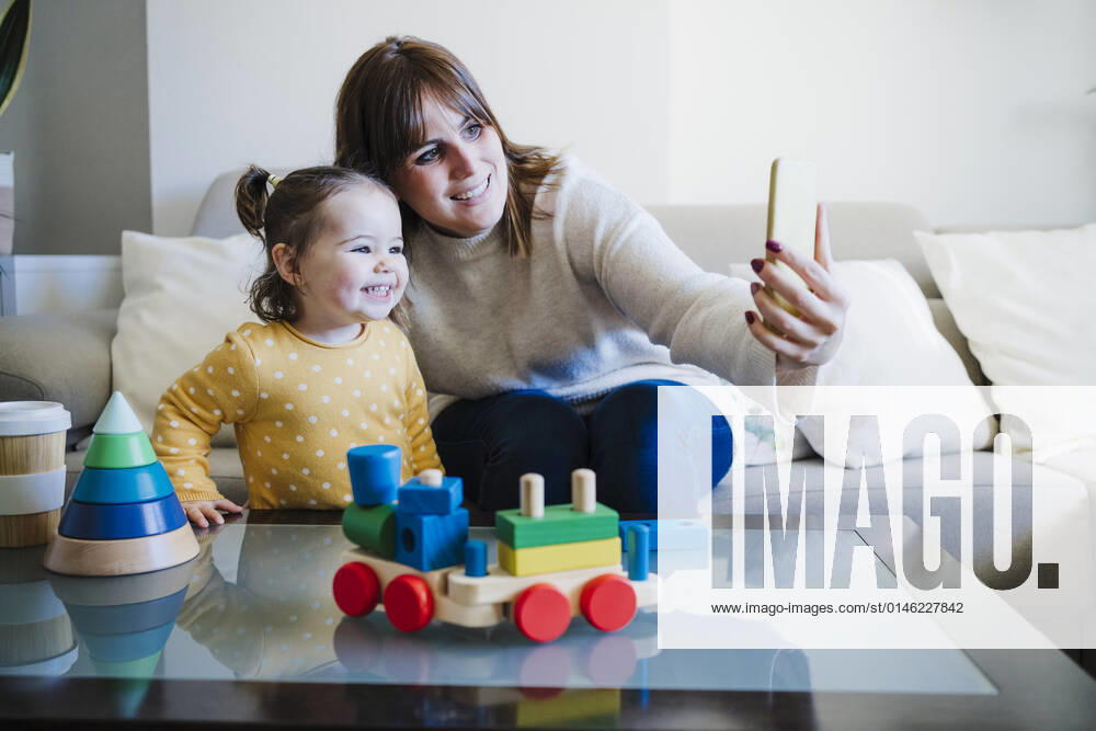 Woman taking selfie with baby girl through mobile phone at home model released property released, EBBF05083